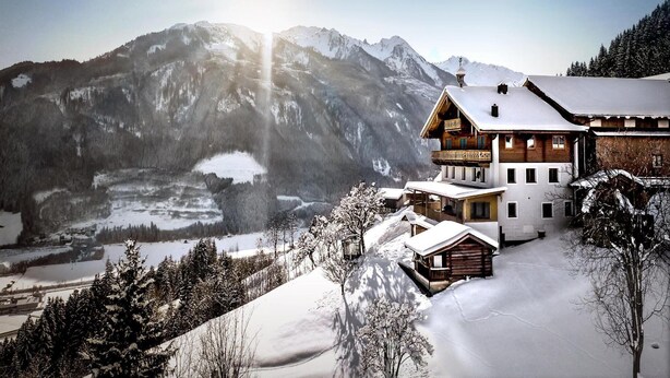 A mountain lodge with a large balcony and a view of snow-covered mountains.
