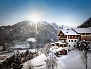 Eine Berghütte mit einem großen Balkon und Blick auf schneebedeckte Berge.