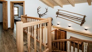 A wooden staircase with a railing, a wall-mounted deer antler, and a wooden rack.