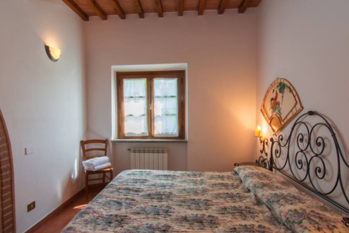 Un dormitorio con una cama, una silla, un ventanal y un radiador.