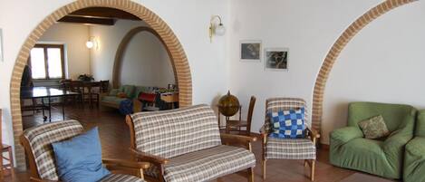 A cozy living room with wooden furniture, a green sofa, and a dining area with a table and chairs.