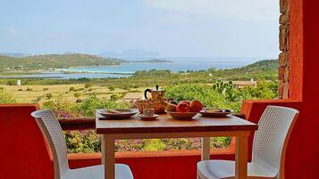 A table with breakfast items and a view of a coastal landscape.