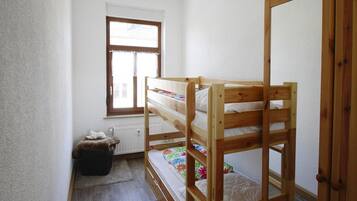 Ein kleines Schlafzimmer mit einem Einzelbett, einem Fenster mit Ausblick, einem Heizkörper und einem kleinen Teppich.