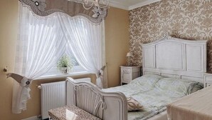 A bedroom with a bed, a nightstand, a chair, and a window with curtains.