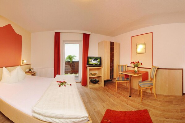 A hotel room with a bed, a TV, a desk with a chair, and a window with curtains. - Apartment in Ischgl in the Mountains (Ischgl)