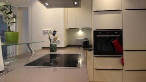 Una cocina moderna con isla de vidrio, electrodomésticos de acero inoxidable y una planta en maceta.