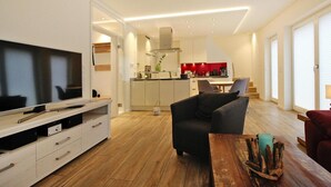 Una sala de estar moderna con un televisor de pantalla plana, un sofá oscuro y una mesa de centro de madera.