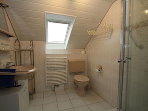 A compact bathroom with a skylight, a toilet, a sink, and a shower. - Dachgeschosswohnung fur 2 Personen in Altenberg (Altenberg)