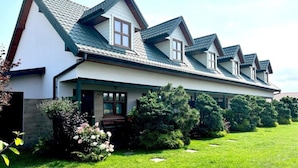A two-story house with a sloped roof, a front porch, and a well-maintained lawn. - Comfortable Holiday Homes Close to the Beach (Mielno)