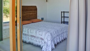 A bedroom with a bed, a wooden headboard, a nightstand, and a shelf.
