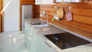 A compact kitchen with wooden walls, a built-in stove, and a refrigerator.