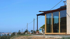 A modern building with large glass windows, a wooden deck, and a view of the cityscape.