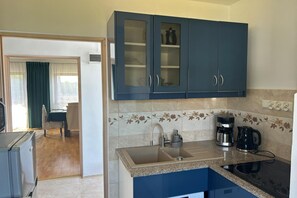 A kitchen with blue cabinets, a sink, a coffee maker, and a stove.