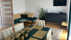 Un salon moderne comprenant un canapé, une table à manger, un téléviseur et un meuble.