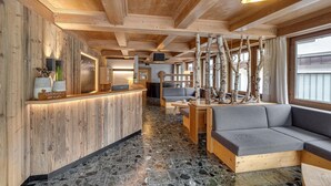Un intérieur en bois comprenant un comptoir d’accueil, un espace détente et de grandes fenêtres.