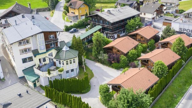 Eine Wohngegend mit verschiedenen Häusern, darunter ein markantes gelbes Gebäude und ein großes weißes Haus mit Gründach.