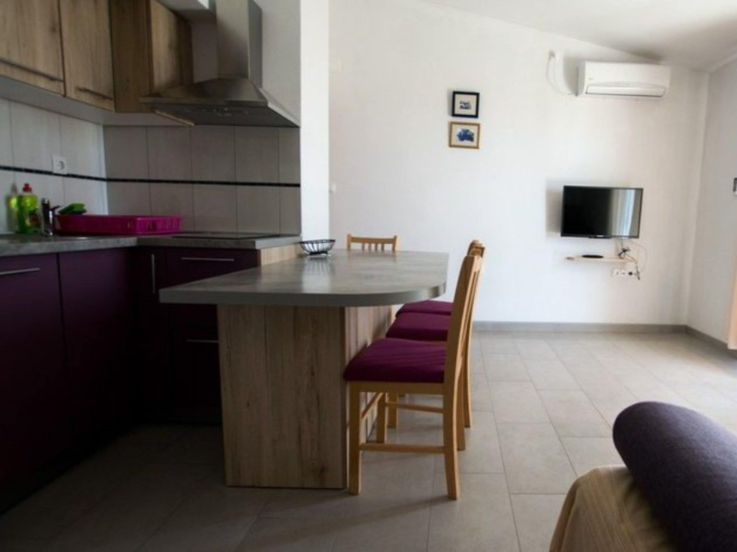 Una cocina moderna con una isla central, armarios de madera y un comedor con mesa y sillas.
