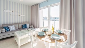 Ein modernes Wohnzimmer mit Sofa, Couchtisch und Essbereich mit Stühlen und einem für zwei Personen gedecktem Tisch.