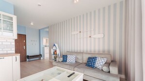 Ein modernes Wohnzimmer mit einer Couch, einem Glastisch und gestreifter Tapete.