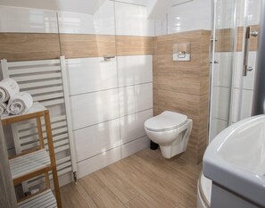 A modern bathroom with a toilet, a shower, and a towel rack. - Comfortable, Convenient Apartment, Pool Included (Postomino)