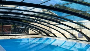 Una piscina interna con tetto in vetro e vista sui dintorni.