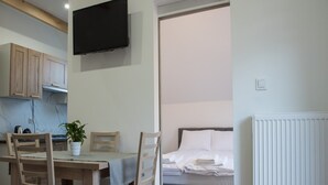 Una camera compatta con un'area pranzo, un letto e una TV a muro.