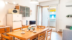 A compact kitchen with a dining area, a microwave, a TV, and a view of the outside balcony. - Apartments Condominio Quercia (San Michele al Tagliamento)