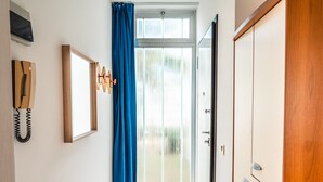 A hallway with a wooden door, a coat rack with clothes, and a telephone. - Apartments Condominio Quercia (San Michele al Tagliamento)