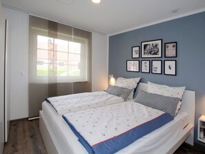 A bedroom with two beds, a window, and framed pictures on the wall. - Ferienwohnung in Ruhiger Lage in Dornumersiel (Dornum)