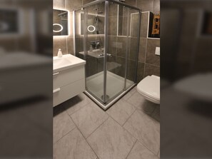 A modern bathroom with a glass-enclosed shower, a white sink, and a toilet. - Ferienwohnung in Ruhiger Lage in Dornumersiel (Dornum)
