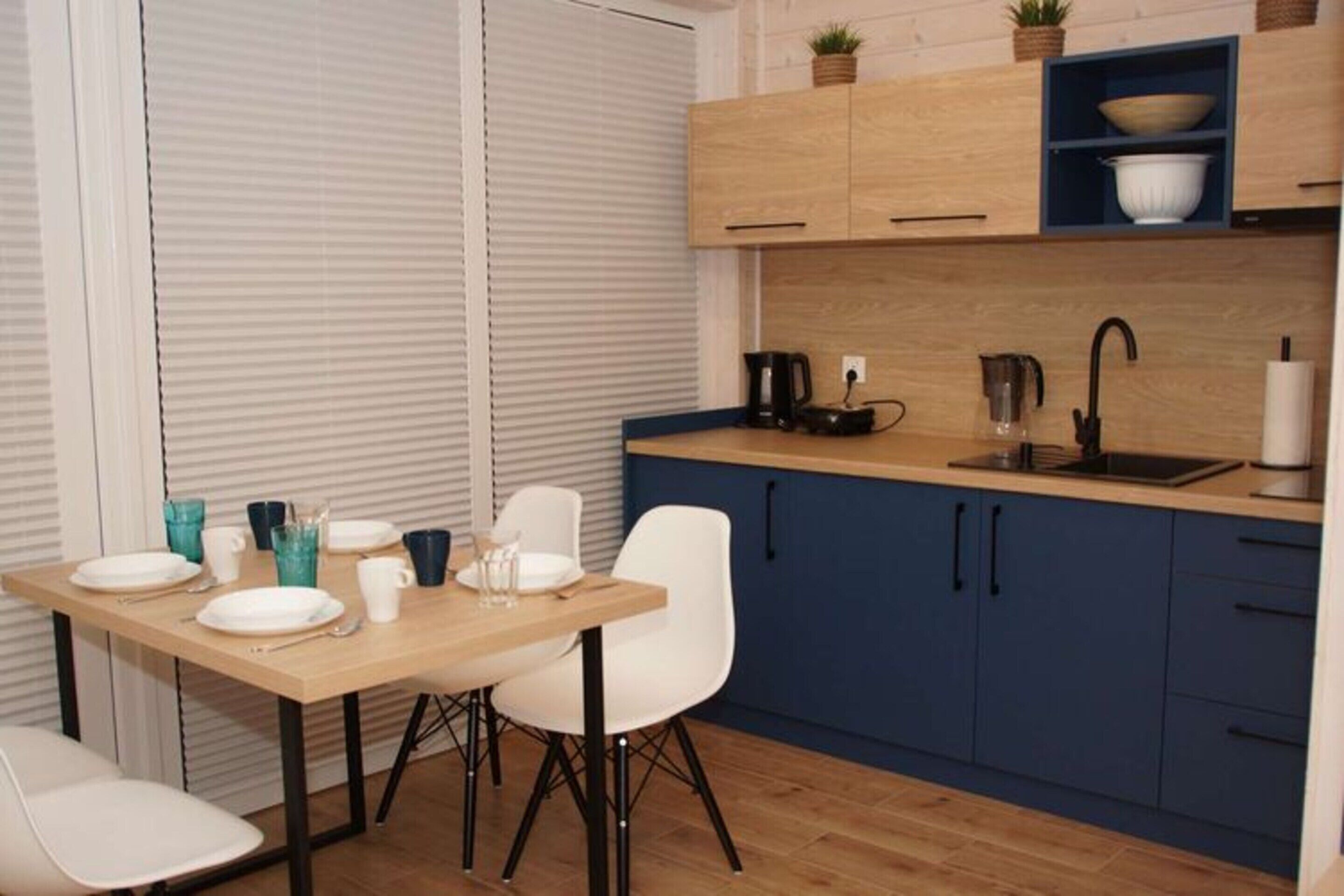 A modern kitchen with wooden cabinets, a countertop, and a dining area with a table and chairs.