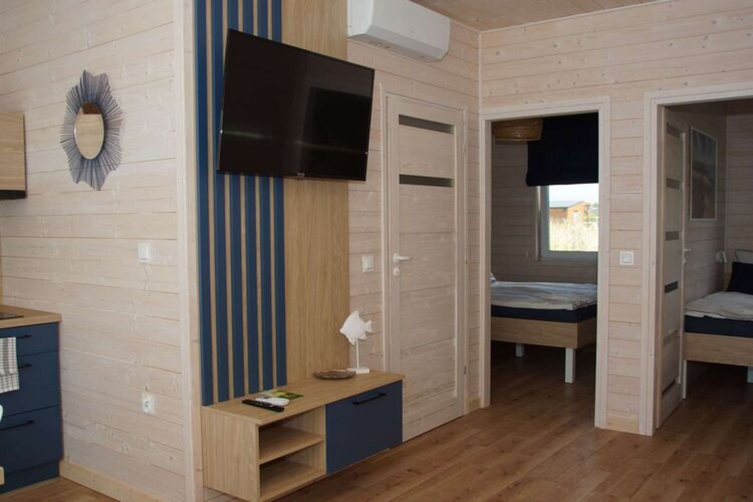Una habitación con televisión, escritorio, dos camas y ventana.