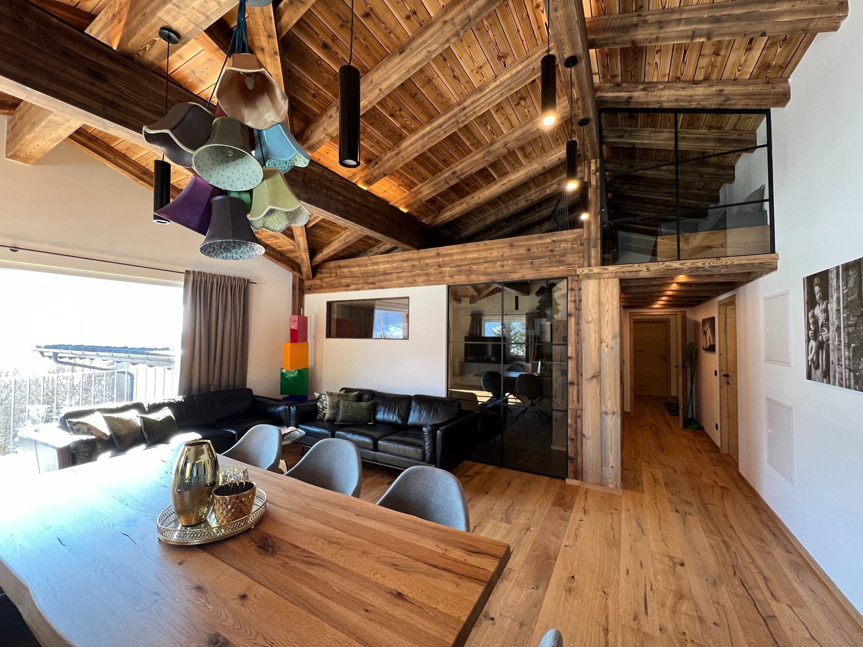 A spacious living area with a wooden ceiling and a dining table with chairs.