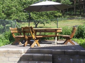 Una mesa de picnic con toldo, rodeada por un muro de ladrillo y una cerca de malla.
