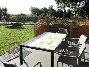 Un patio al aire libre con una mesa y sillas, rodeado por un cerco de madera y follaje.