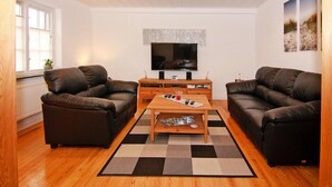 A living room with two leather sofas, a wooden coffee table, a flat-screen TV, and a patterned rug. - Ferienhaus in Rehm-flehde-bargen mit Gemeinsamer Sauna (Rehm-Flehde-Bargen)