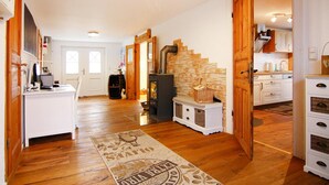 A spacious kitchen with wooden floors, a stone wall, and a built-in wood stove. - Ferienhaus in Rehm-flehde-bargen mit Gemeinsamer Sauna (Rehm-Flehde-Bargen)