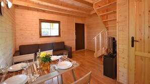 A cozy wooden cabin interior with a dining area, sofa, and a TV. - Year-round Holiday House Near the Sea, Pustkowo (Rewal)