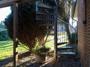A metal staircase leading to a covered area with a potted plant at the base. - Comfortable Holiday Apartment in St. Peter Ording (St. Peter-Ording)