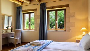 Une chambre à coucher avec un lit, un bureau, une chaise et deux fenêtres avec des rideaux.