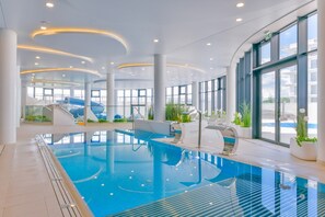 An indoor swimming pool with clear water, surrounded by white columns and large windows. - Aparthotel With Pools, Near the Sea, Kolobrzeg (Kolobrzeg)