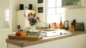 A kitchen with a wooden countertop, a white pitcher with flowers, a fruit bowl, and a toaster. - Reetdachhaus am Bodden mit Sauna (Fuhlendorf)