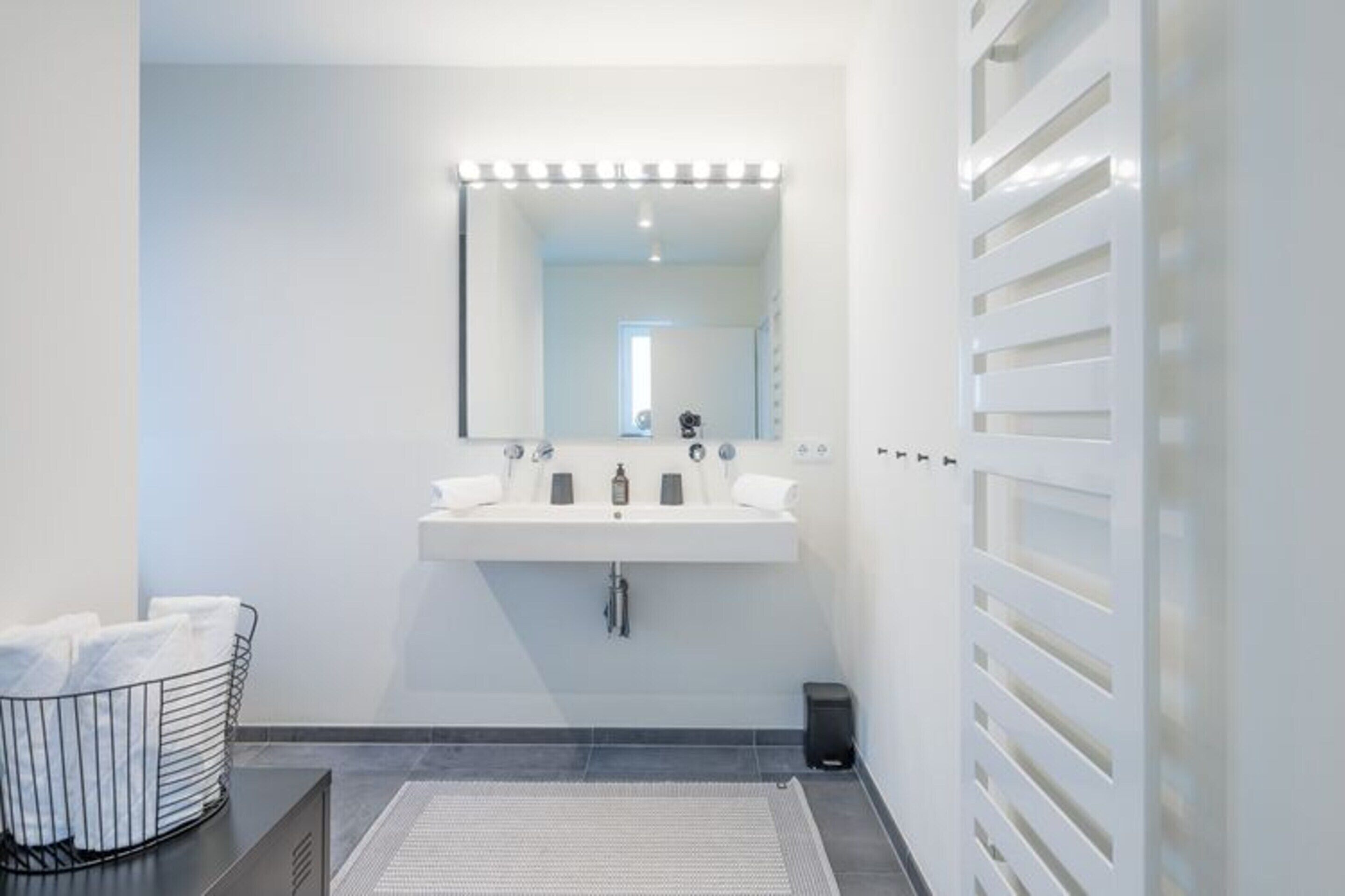 Un bagno moderno con un ampio specchio, lavandino bianco e porta asciugamani.