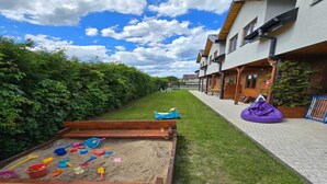 A pathway lined with a wooden play area and a row of houses with a paved walkway. - Holiday Homes Close to the Seaside Beach (Mielno)