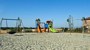 Ein Spielplatz mit Schaukeln und Rutschen an einem Sandstrand.