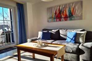 Un salon avec un canapé, une table basse, un tableau et une vue par la fenêtre.