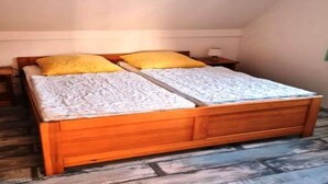 Camera con un letto singolo, struttura in legno, due cuscini, copripiumino bianco e lampada a sospensione.