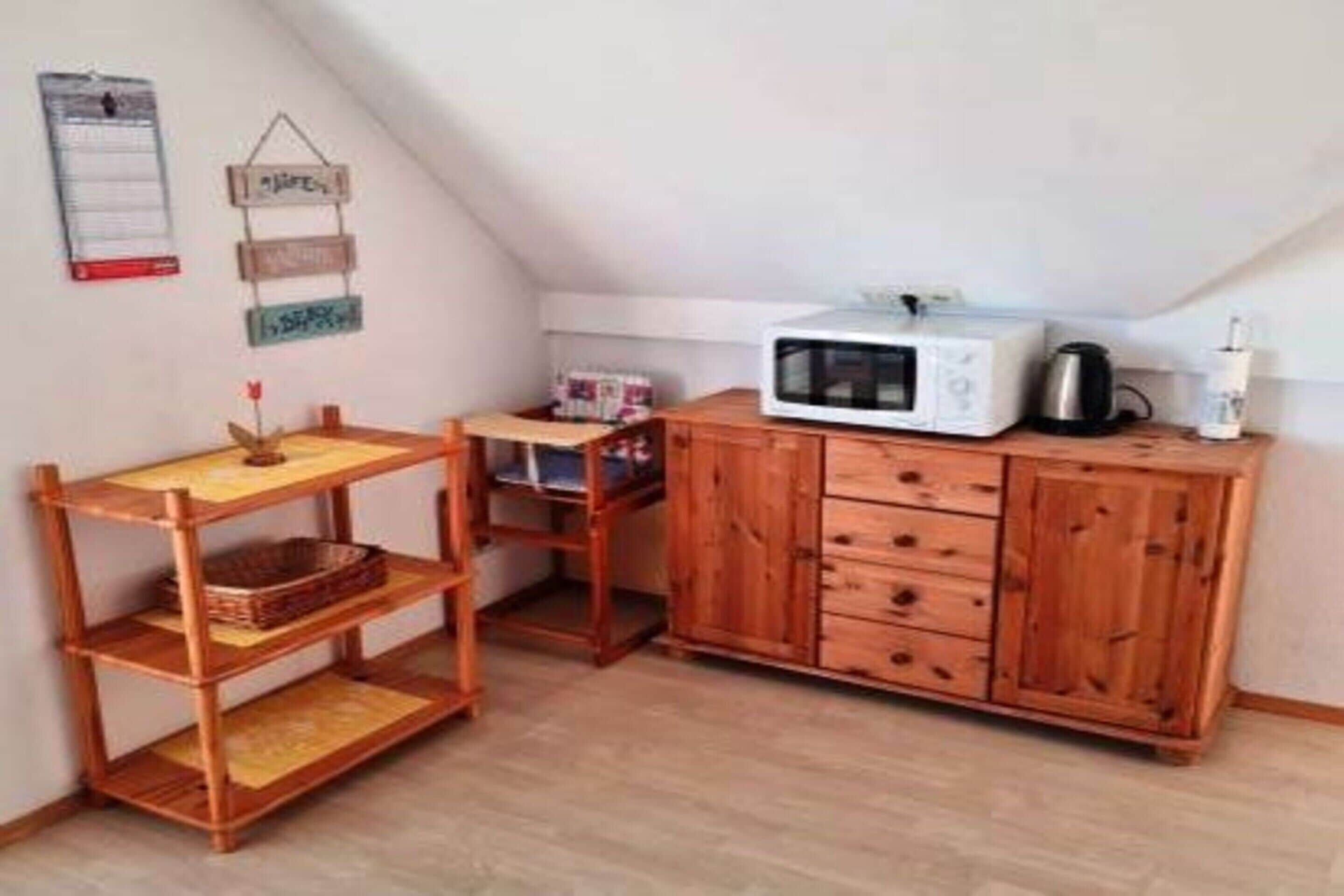 A compact kitchen with a microwave, wooden cabinets, and a small table.