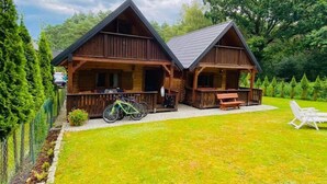 A two-story wooden cabin with a porch and a covered patio area. - Cozy Cottage With a Huge Garden, Jaroslawiec (Postomino)