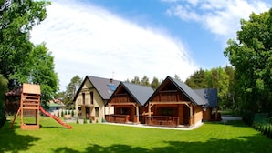 A wooden lodge with a red slide and a well-maintained lawn. - Cozy Cottage With a Huge Garden, Jaroslawiec (Postomino)